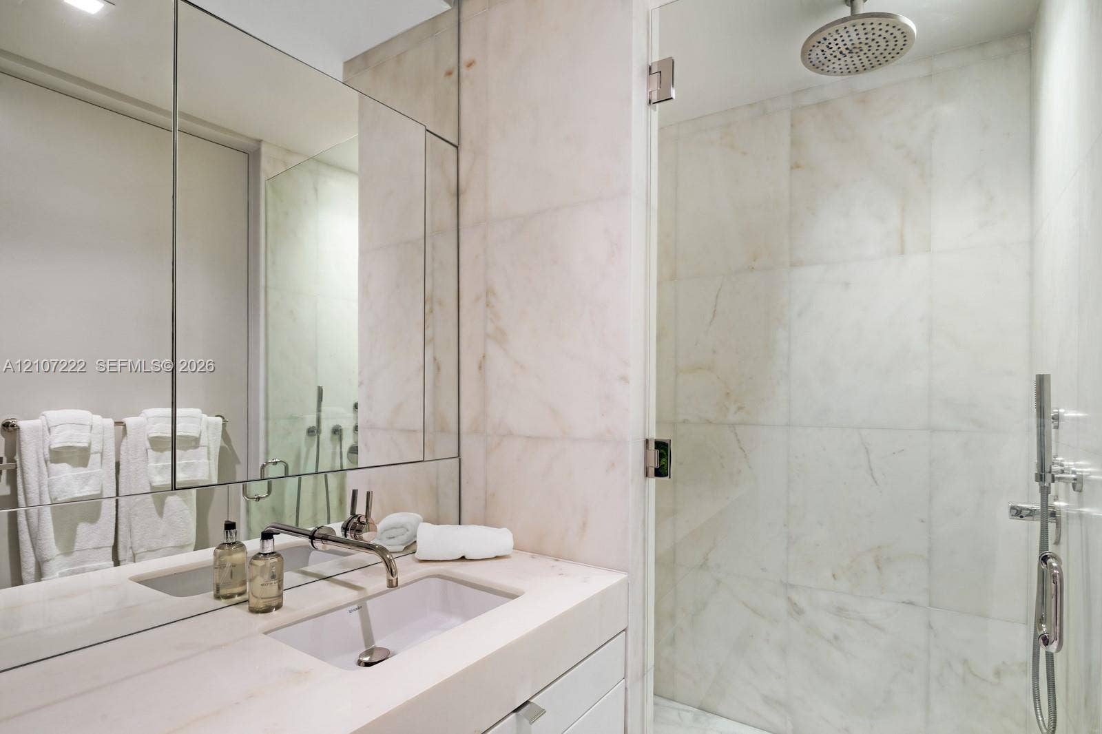 1300 Monad Terrace, #2F, Miami Beach, FL 33139 Bathroom featuring a floating vanity with a stone countertop and integrated sink, full-height wall mirror, stone-tile walk-in shower with a glass door, rainfall showerhead, and a hand-held shower sprayer