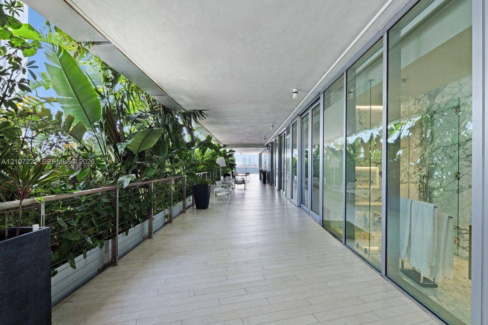 1300 Monad Terrace, #2F, Miami Beach, FL 33139 Expansive covered terrace featuring light-toned tile flooring, floor-to-ceiling glass panel walls, integrated railing, and built-in landscape planters