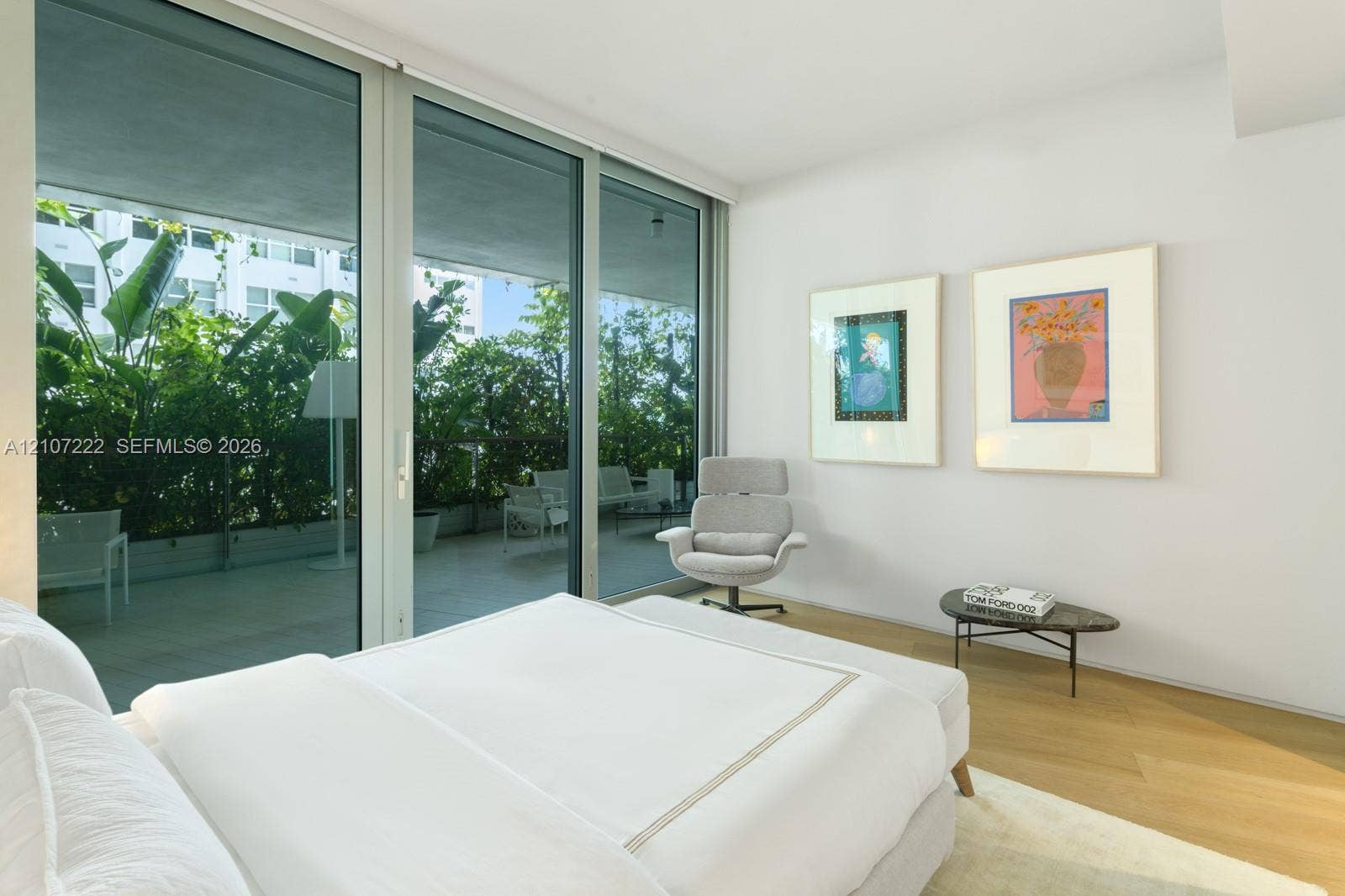 1300 Monad Terrace, #2F, Miami Beach, FL 33139 Floor-to-ceiling glass sliding doors, private covered balcony with glass railing, and light-tone wood-finish flooring