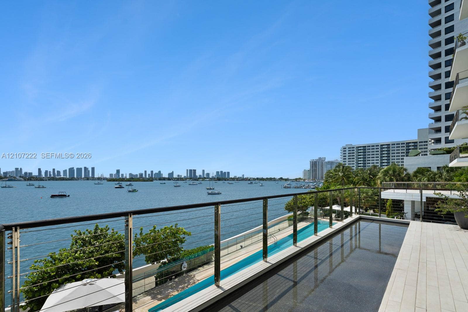 1300 Monad Terrace, #2F, Miami Beach, FL 33139 Elevated terrace featuring stone tile flooring, an infinity-edge pool, and a metal railing with horizontal wire cabling