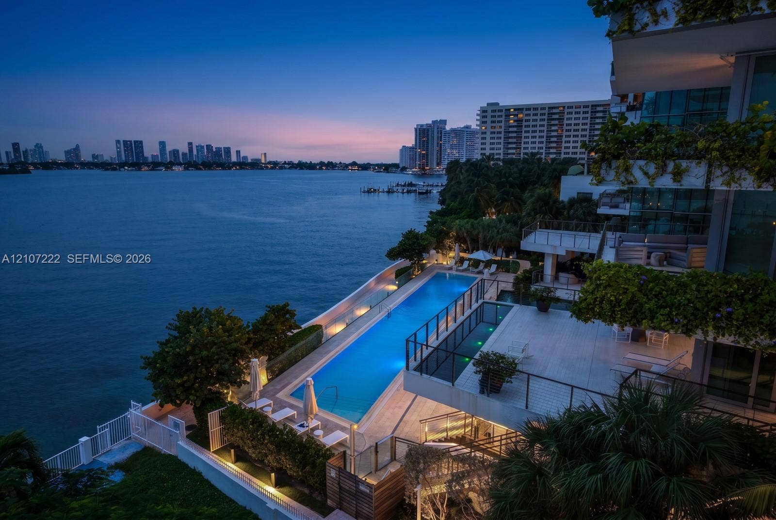 1300 Monad Terrace, #2F, Miami Beach, FL 33139 Waterfront property featuring a rectangular lap pool, expansive tiled terrace, tiered multi-level balconies, and glass panel railings