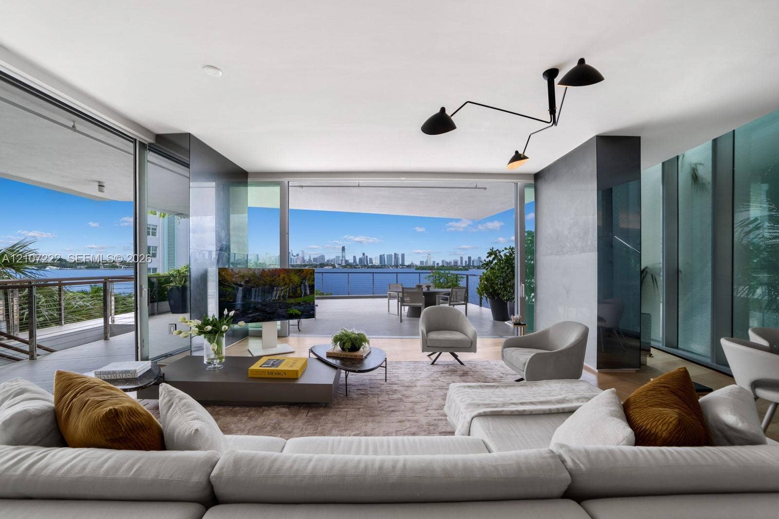 1300 Monad Terrace, #2F, Miami Beach, FL 33139 Expansive living space featuring floor-to-ceiling glass walls, integrated sliding door system, matte black multi-arm ceiling fixture, and deep covered balcony