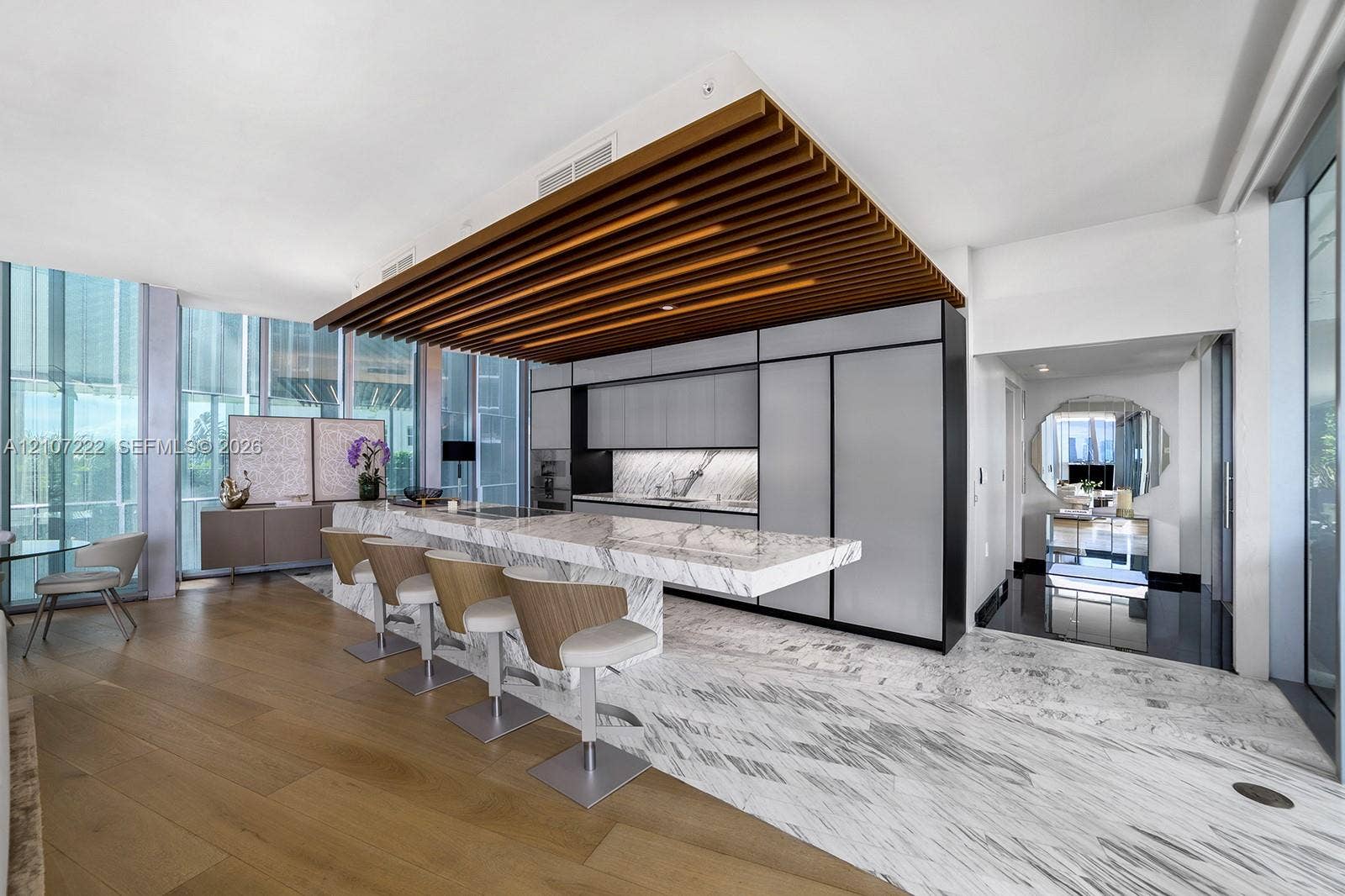 1300 Monad Terrace, #2F, Miami Beach, FL 33139 Gourmet kitchen featuring a stone-topped waterfall island, custom flat-panel cabinetry, integrated appliances, decorative wood slat ceiling detail, and mixed wood-finish and stone flooring