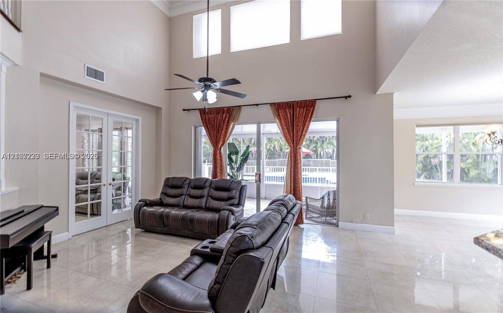 5280 NW 95th Avenue, Coral Springs, Coral Springs, FL 33076 High-ceilinged room featuring neutral tile flooring, clerestory windows, a dual-pane sliding glass door, and white-trimmed French doors