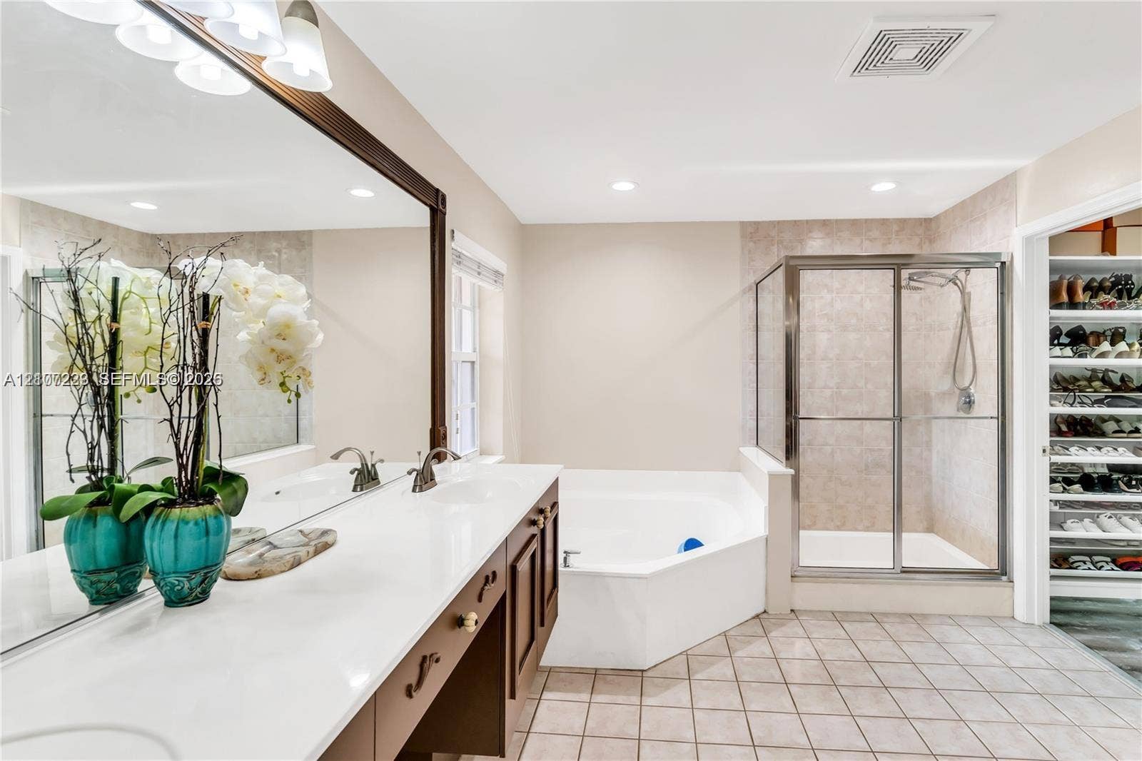 5280 NW 95th Avenue, Coral Springs, Coral Springs, FL 33076 Double vanity with white solid-surface countertops, large wall-mounted mirror, soaking tub, glass-enclosed shower, and built-in shelving unit