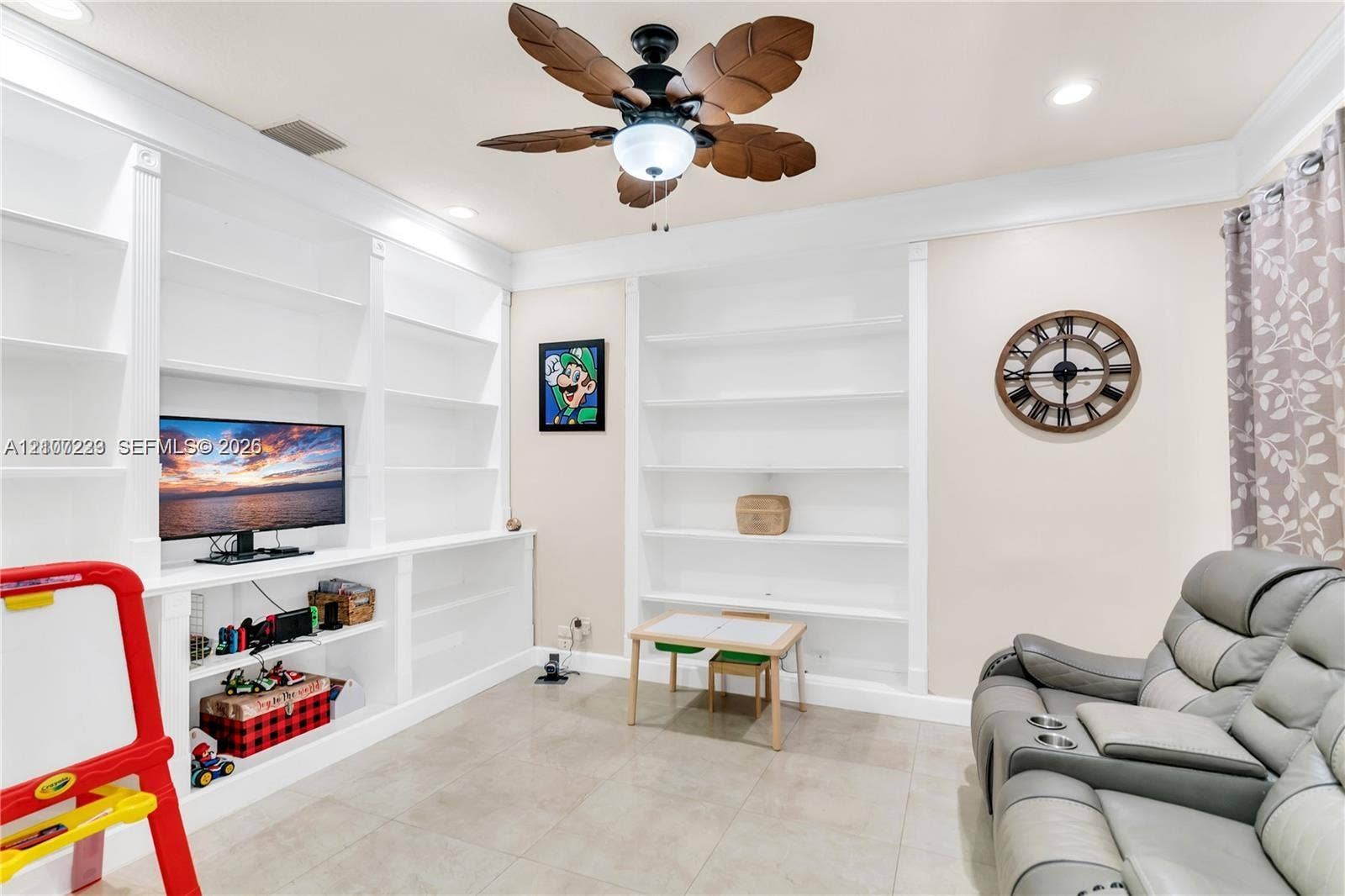 5280 NW 95th Avenue, Coral Springs, Coral Springs, FL 33076 Expansive built-in white shelving units, palm-leaf inspired ceiling fan, crown molding, and large-format tile flooring