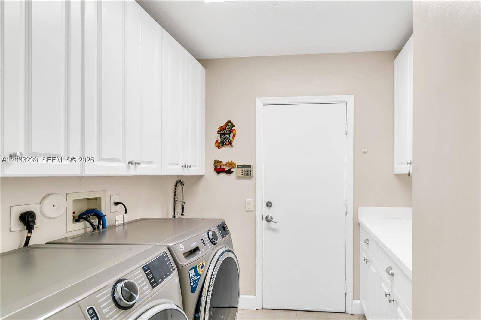 5280 NW 95th Avenue, Coral Springs, Coral Springs, FL 33076 Utility room featuring white cabinetry, solid-surface countertops, and a dedicated wash basin