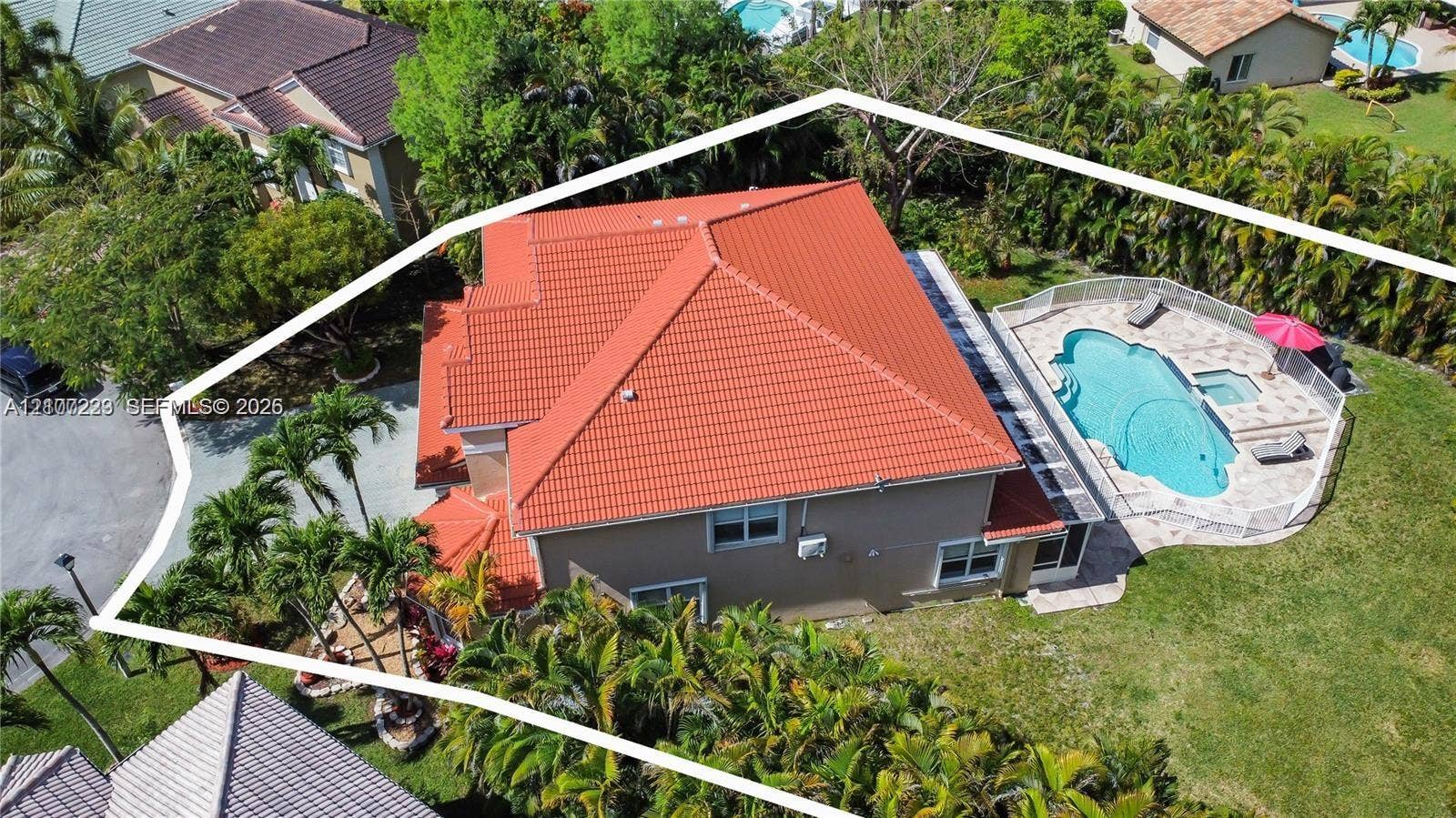 5280 NW 95th Avenue, Coral Springs, Coral Springs, FL 33076 Aerial view of residential property featuring a tiled roof, an inground swimming pool with integrated spa, paved pool deck, and mature tropical landscaping