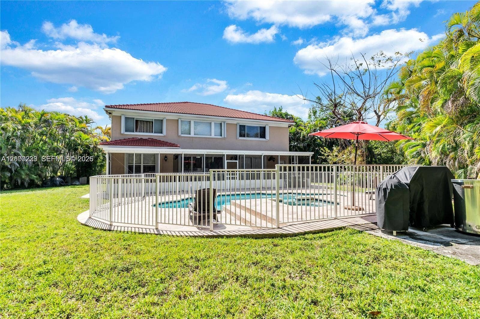 5280 NW 95th Avenue, Coral Springs, Coral Springs, FL 33076 Two-story exterior with a tiled roof, featuring an in-ground pool, screened-in patio, and white metal perimeter fencing situated on a lawn