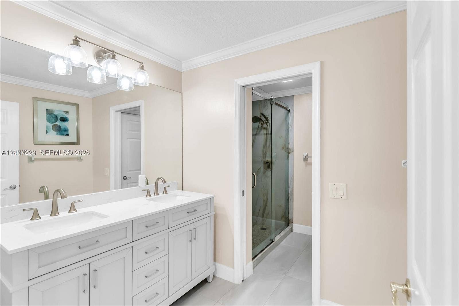 5280 NW 95th Avenue, Coral Springs, Coral Springs, FL 33076 Double-sink vanity featuring stone-surfaced countertops, brushed nickel fixtures, crown molding, and a full-width mirror, accompanied by a glass-enclosed shower stall with tile flooring