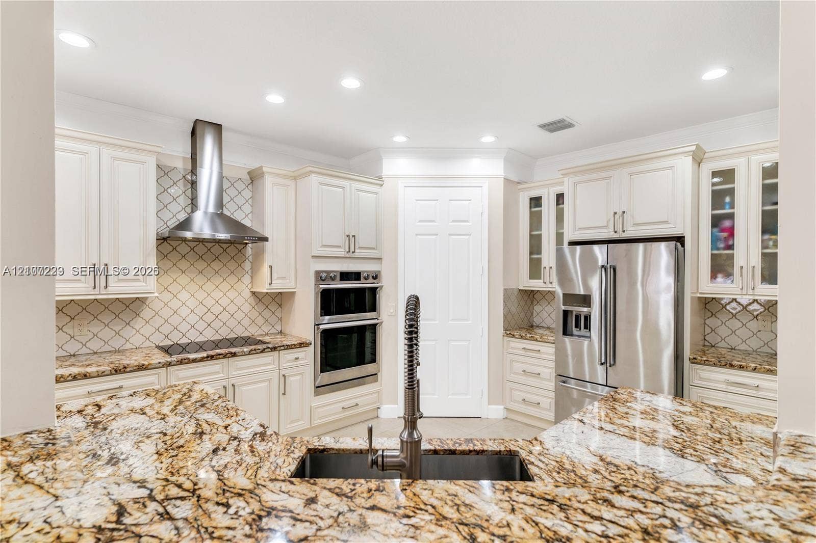 5280 NW 95th Avenue, Coral Springs, Coral Springs, FL 33076 Kitchen featuring stone countertops, white cabinetry with glass-front accents, stainless steel appliances, a diamond-pattern tile backsplash, and recessed lighting