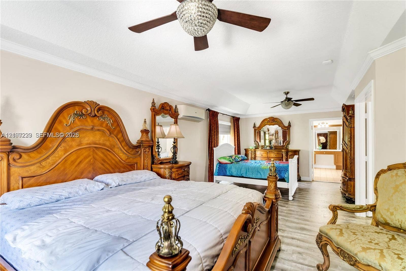 5280 NW 95th Avenue, Coral Springs, Coral Springs, FL 33076 Tray ceiling featuring dual crystal-accented ceiling fans, wood-finish flooring, and a wall-mounted ductless climate control unit