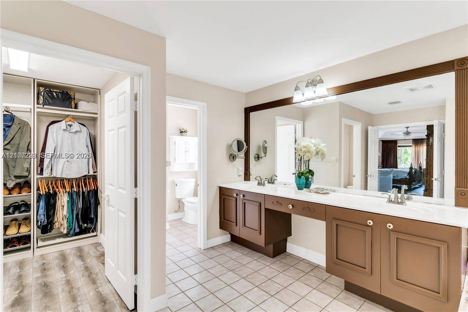 5280 NW 95th Avenue, Coral Springs, Coral Springs, FL 33076 Dual-sink vanity with built-in cabinetry and stone-surface countertop, full-width mirror, tile flooring, and walk-in closet with integrated shelving