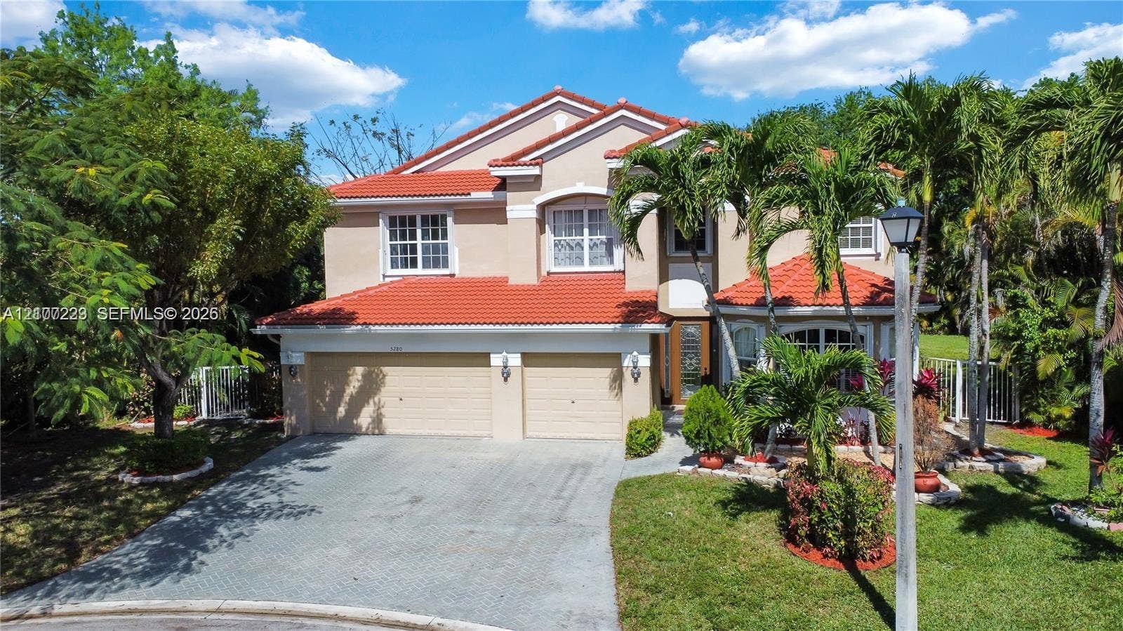 5280 NW 95th Avenue, Coral Springs, Coral Springs, FL 33076 Two-story exterior featuring a terracotta-tiled roof, stucco facade, and an attached two-car garage with a paved driveway