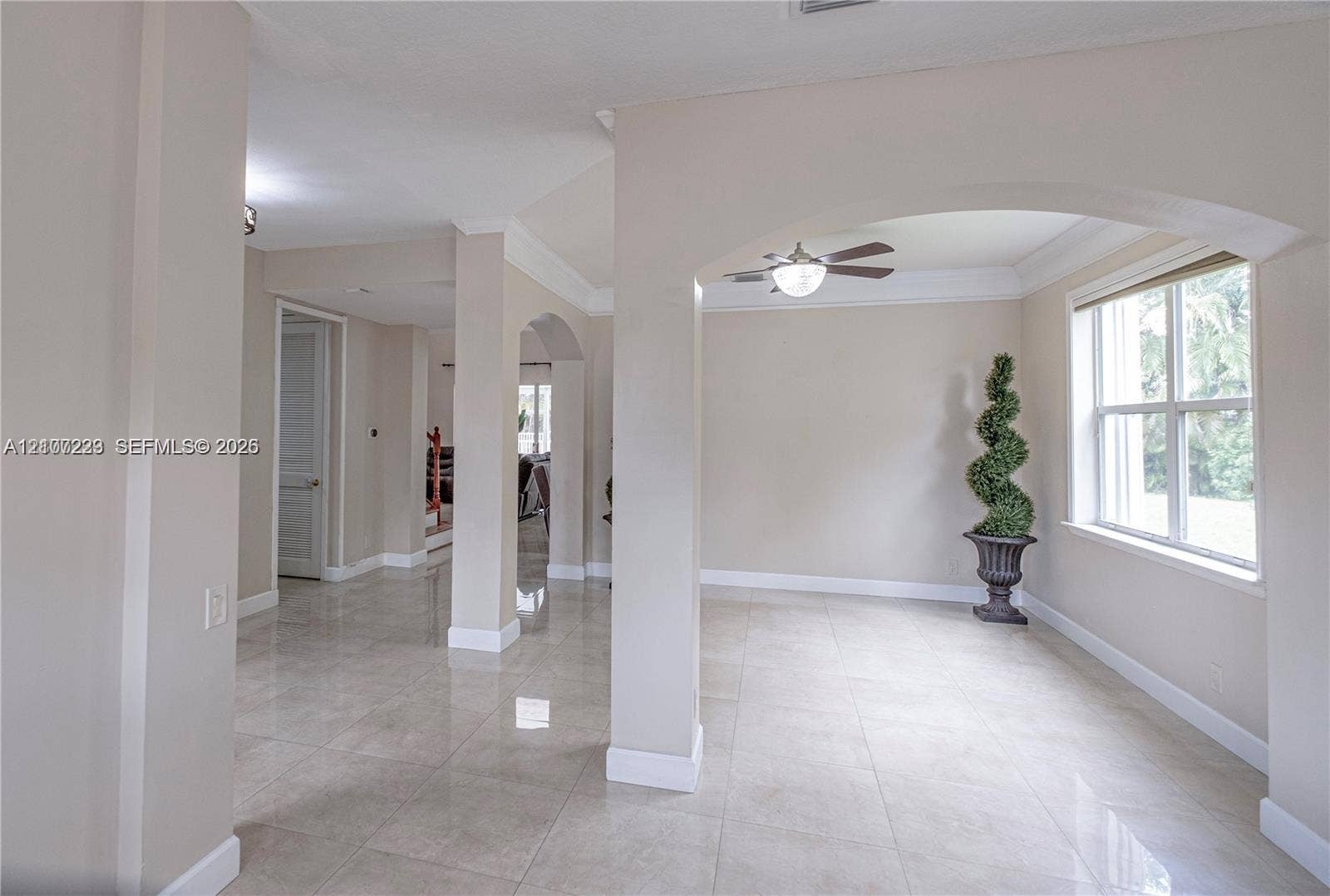 5280 NW 95th Avenue, Coral Springs, Coral Springs, FL 33076 Interior space featuring arched architectural detailing, tile flooring, vaulted ceilings with a mounted light-fixture ceiling fan, and large windows