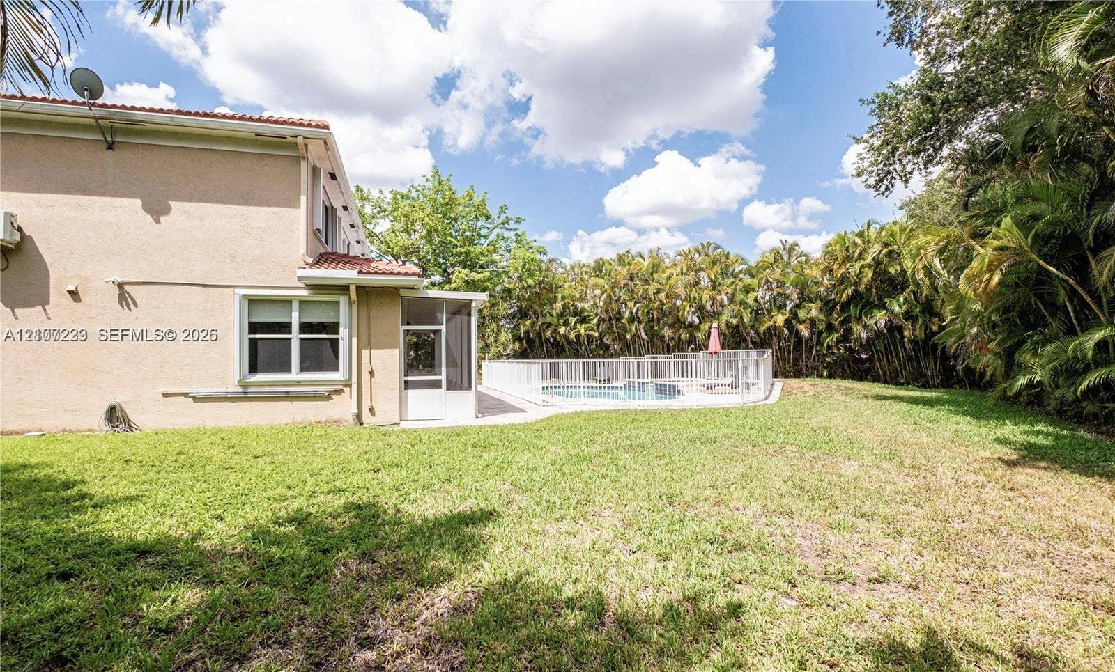 5280 NW 95th Avenue, Coral Springs, Coral Springs, FL 33076 Stucco exterior with a tiled roof, enclosed swimming pool, and expansive grass yard bordered by mature vegetation