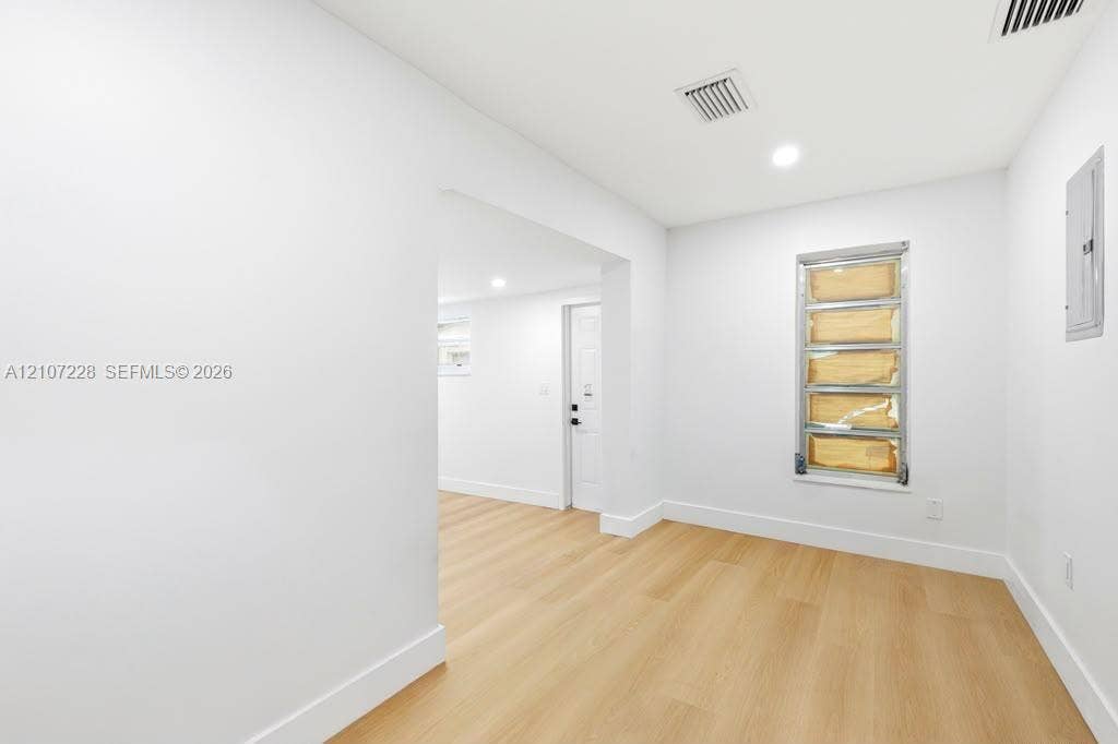 Interior space featuring wood-finish flooring, recessed lighting, and a multi-pane louvered window