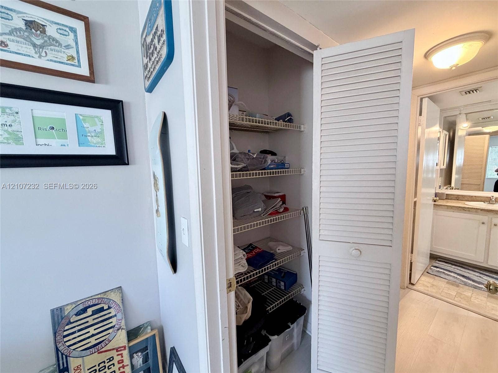 Storage closet featuring white louvered doors and multi-tier wire shelving