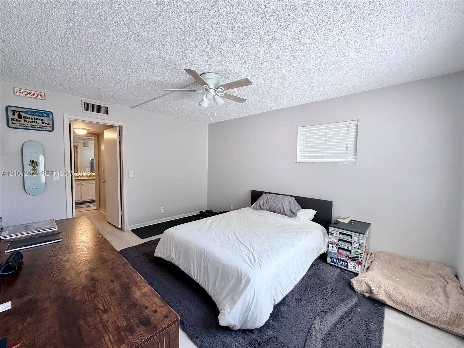Room featuring light-toned walls, wood-finish flooring, a ceiling-mounted fan with integrated lighting, and a horizontal-slat window blind