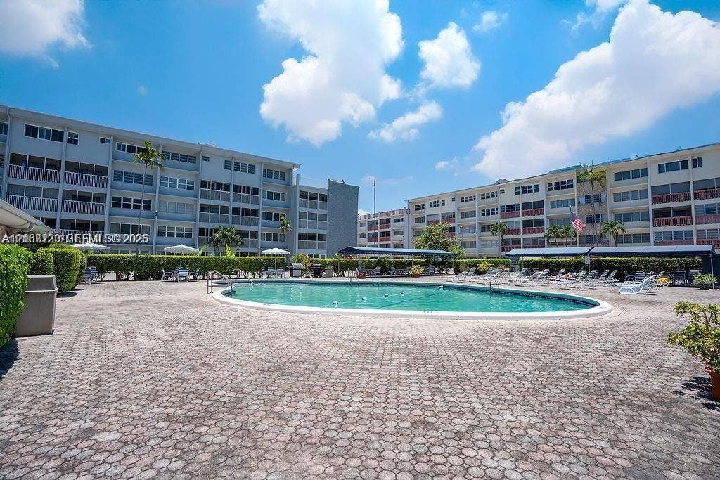 215 SE 3rd Avenue, #102D, Hallandale Beach, Hallandale Beach, FL 33009 Oval swimming pool with a paved deck, surrounded by manicured hedges and covered seating areas