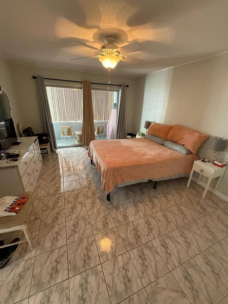 215 SE 3rd Avenue, #102D, Hallandale Beach, Hallandale Beach, FL 33009 Tile flooring with neutral veining, ceiling fan with integrated lighting, and sliding glass doors providing access to a balcony