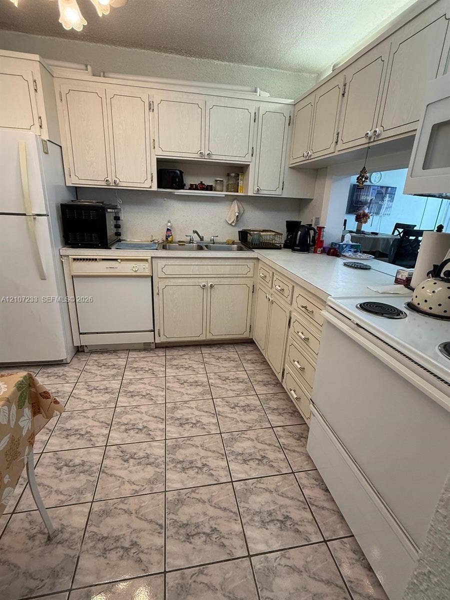 215 SE 3rd Avenue, #102D, Hallandale Beach, Hallandale Beach, FL 33009 Kitchen featuring white cabinetry, solid-surface countertops, dual-basin stainless steel sink, and ceramic tile flooring