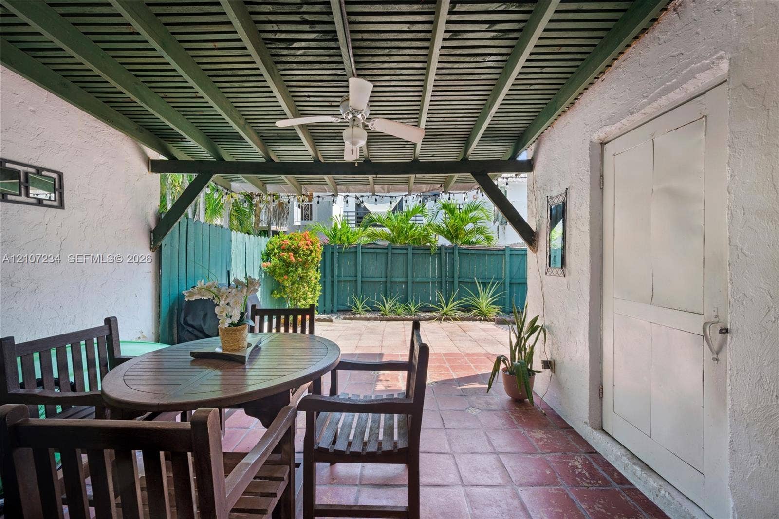 13507 NE 24th Court, North Miami, FL 33181 Covered patio featuring a slatted wooden ceiling with a ceiling fan, terra cotta tile flooring, stucco exterior walls, and a privacy fence