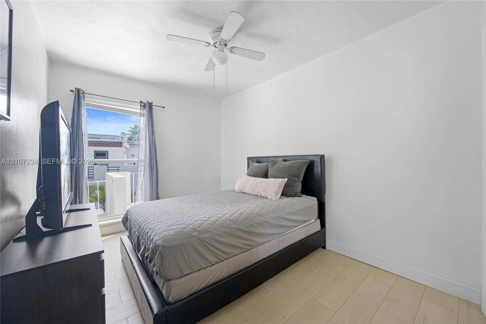 13507 NE 24th Court, North Miami, FL 33181 Neutral-toned wood-finish flooring, white wall finishes, and a four-blade ceiling fan with integrated lighting