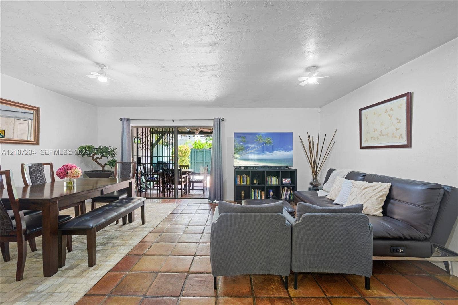 13507 NE 24th Court, North Miami, FL 33181 Open-concept living space featuring large-format ceramic tile flooring, dual ceiling-mounted lighting fixtures, and sliding glass doors providing access to the rear exterior