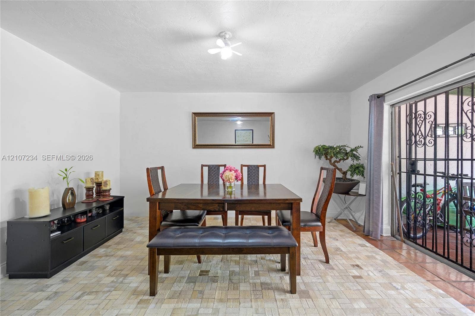 13507 NE 24th Court, North Miami, FL 33181 Interior space featuring a textured tile floor, sliding glass door with a decorative metal security screen, and a flush-mount ceiling light fixture