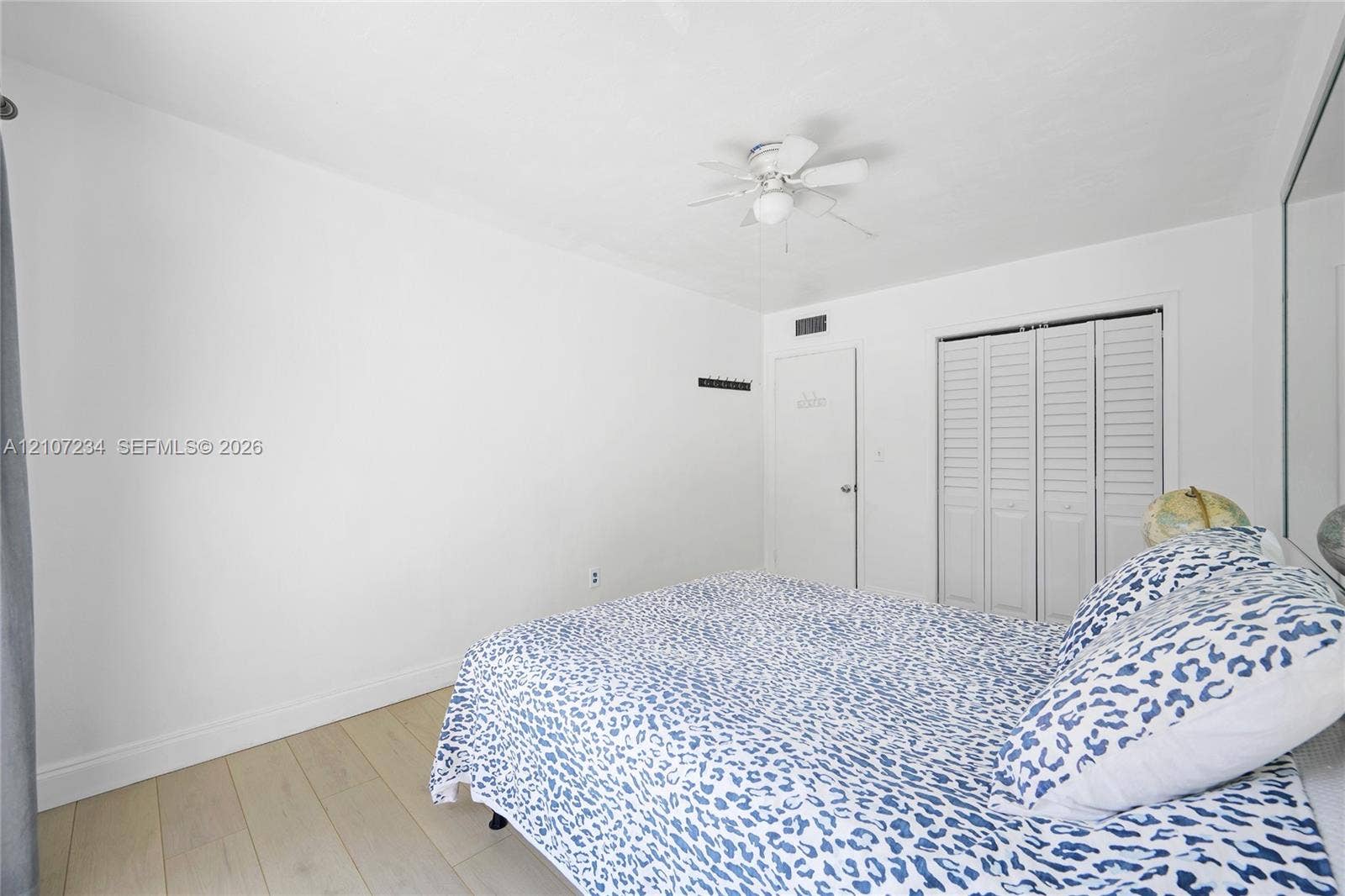 13507 NE 24th Court, North Miami, FL 33181 Neutral-toned wood-finish flooring, ceiling fan with integrated lighting, and white louvered bifold closet doors