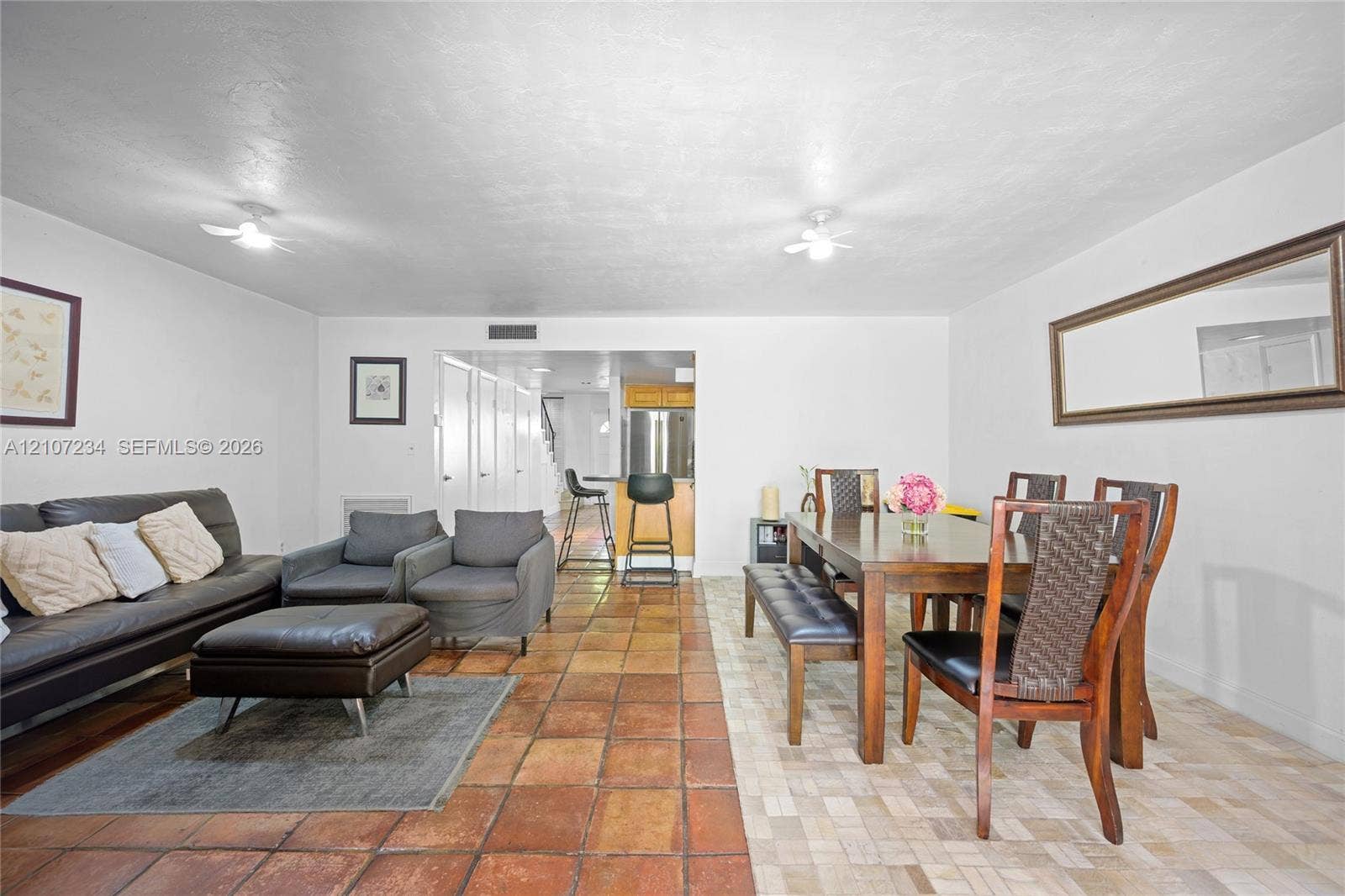 13507 NE 24th Court, North Miami, FL 33181 Open-concept floor plan featuring large-format terra cotta tile flooring, dual ceiling-mounted light fixtures, and a wall-mounted rectangular mirror