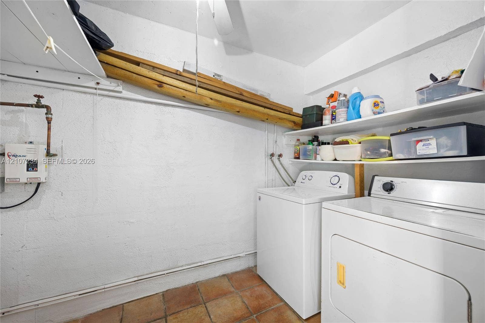 13507 NE 24th Court, North Miami, FL 33181 Utility area featuring terra cotta tile flooring, white-painted masonry walls, and integrated wall-mounted shelving