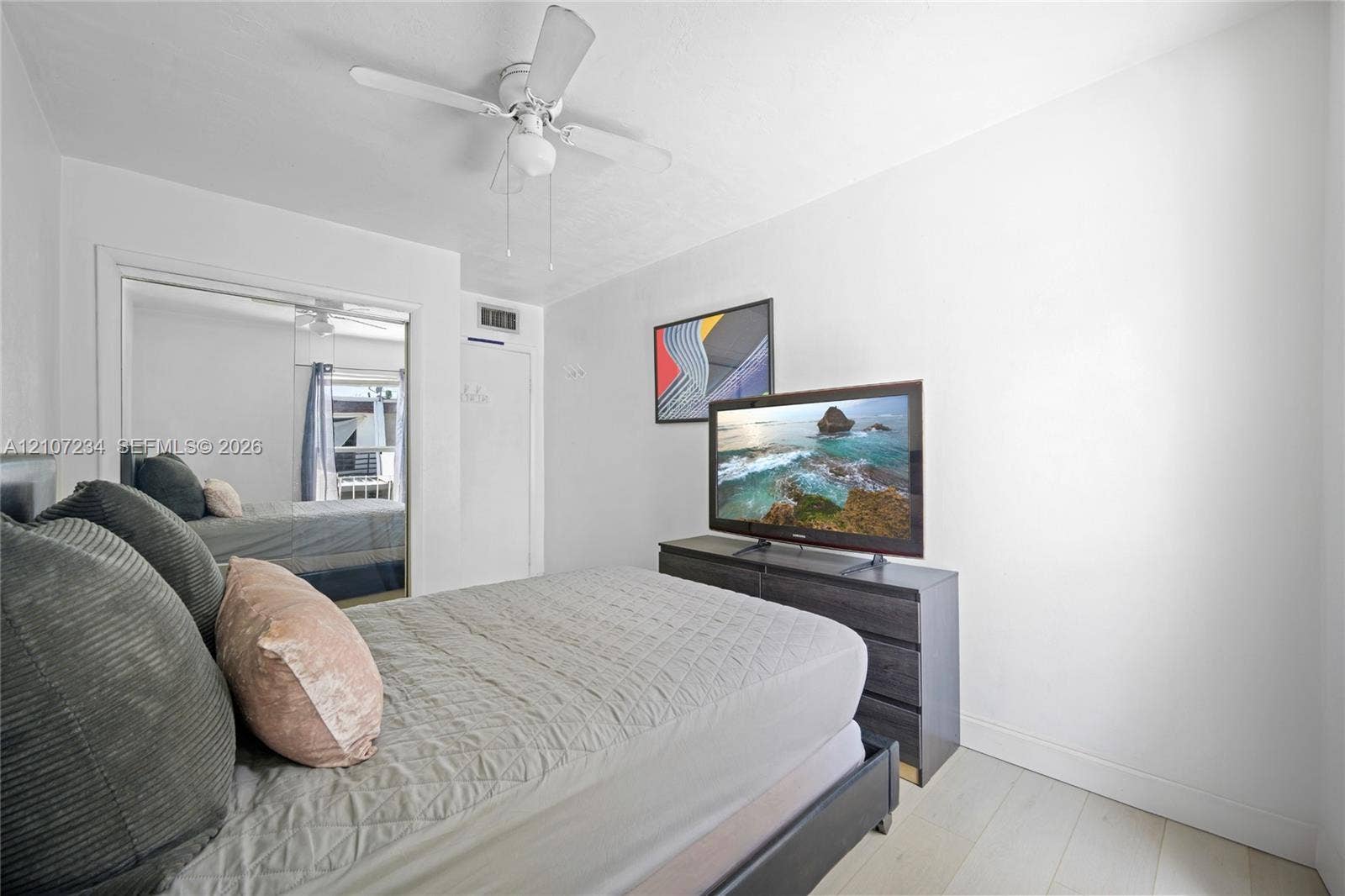 13507 NE 24th Court, North Miami, FL 33181 Neutral walls, wood-finish flooring, ceiling fan with integrated lighting, and dual-panel sliding mirror closet doors