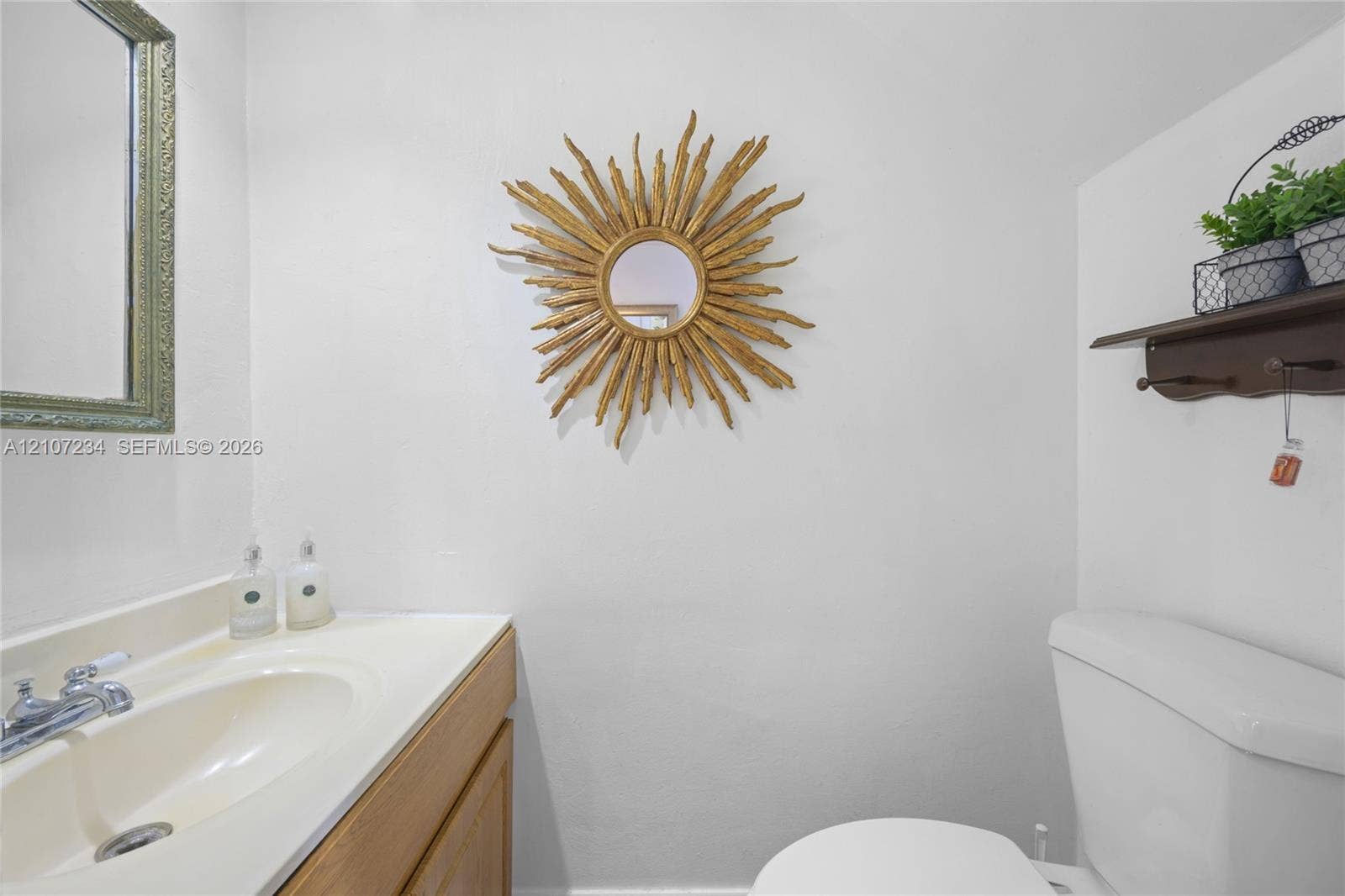 13507 NE 24th Court, North Miami, FL 33181 Wood-finish vanity featuring an integrated basin and a chrome-finish faucet, complemented by a wall-mounted wooden shelf
