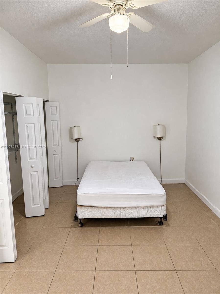2529 NE 41st Terrace, Homestead, FL 33033 Room featuring neutral tile flooring, bi-fold closet doors, and a ceiling-mounted light fixture with a fan