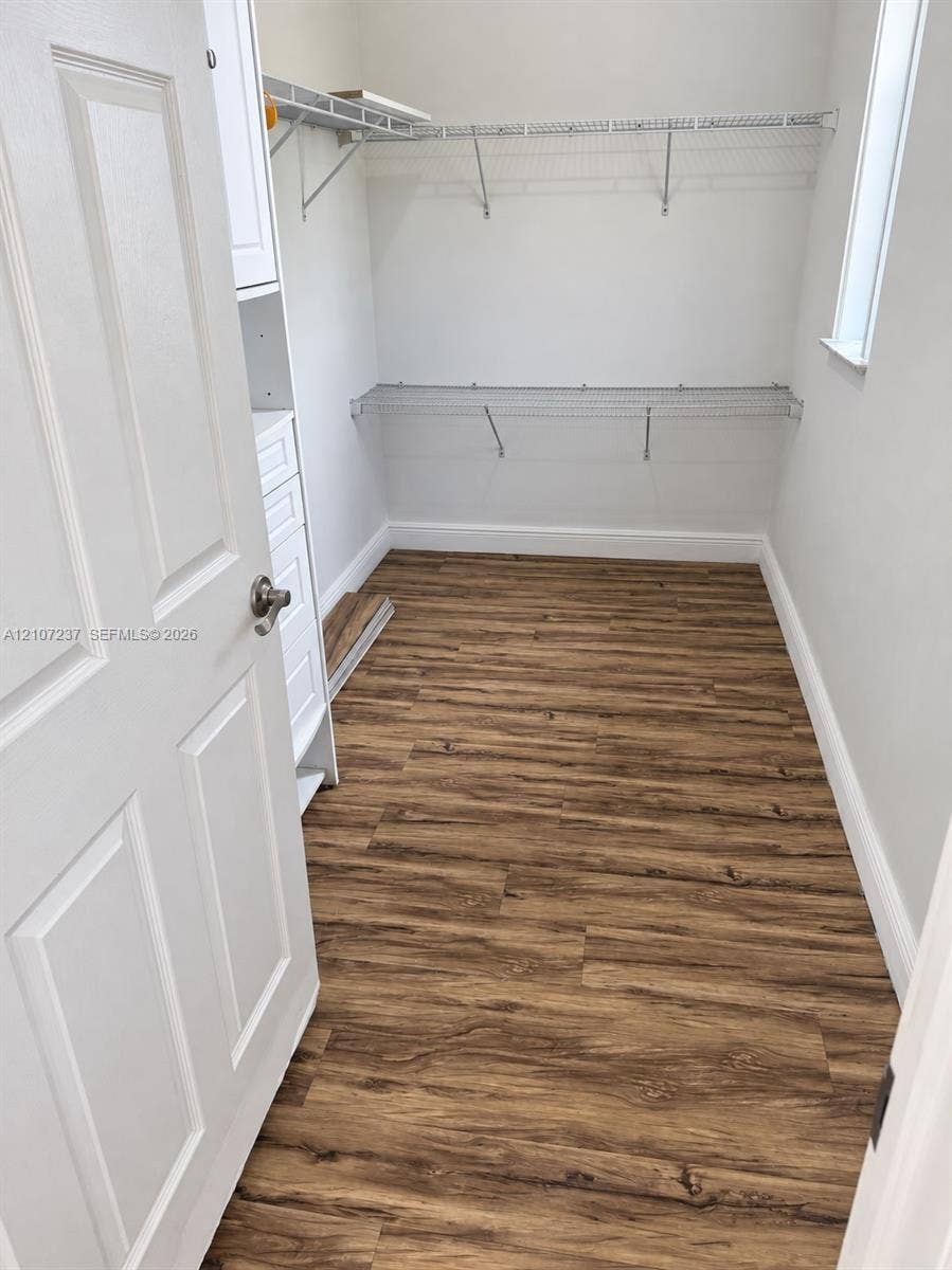2529 NE 41st Terrace, Homestead, FL 33033 Storage space featuring wood-finish flooring, white built-in cabinetry with drawers, and multi-tier wire shelving