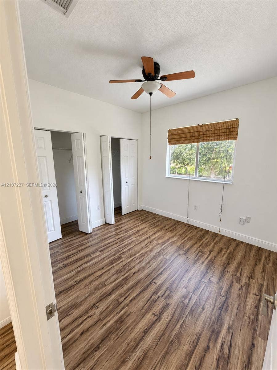 2529 NE 41st Terrace, Homestead, FL 33033 Wood-finish flooring, dual reach-in closets with panel doors, and a ceiling fan with integrated lighting