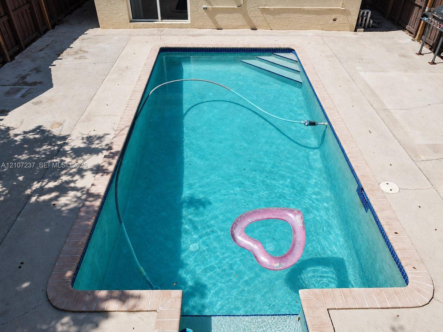 2529 NE 41st Terrace, Homestead, FL 33033 Rectangular in-ground swimming pool featuring a brick-tiled coping, built-in entry steps, and a concrete patio surround