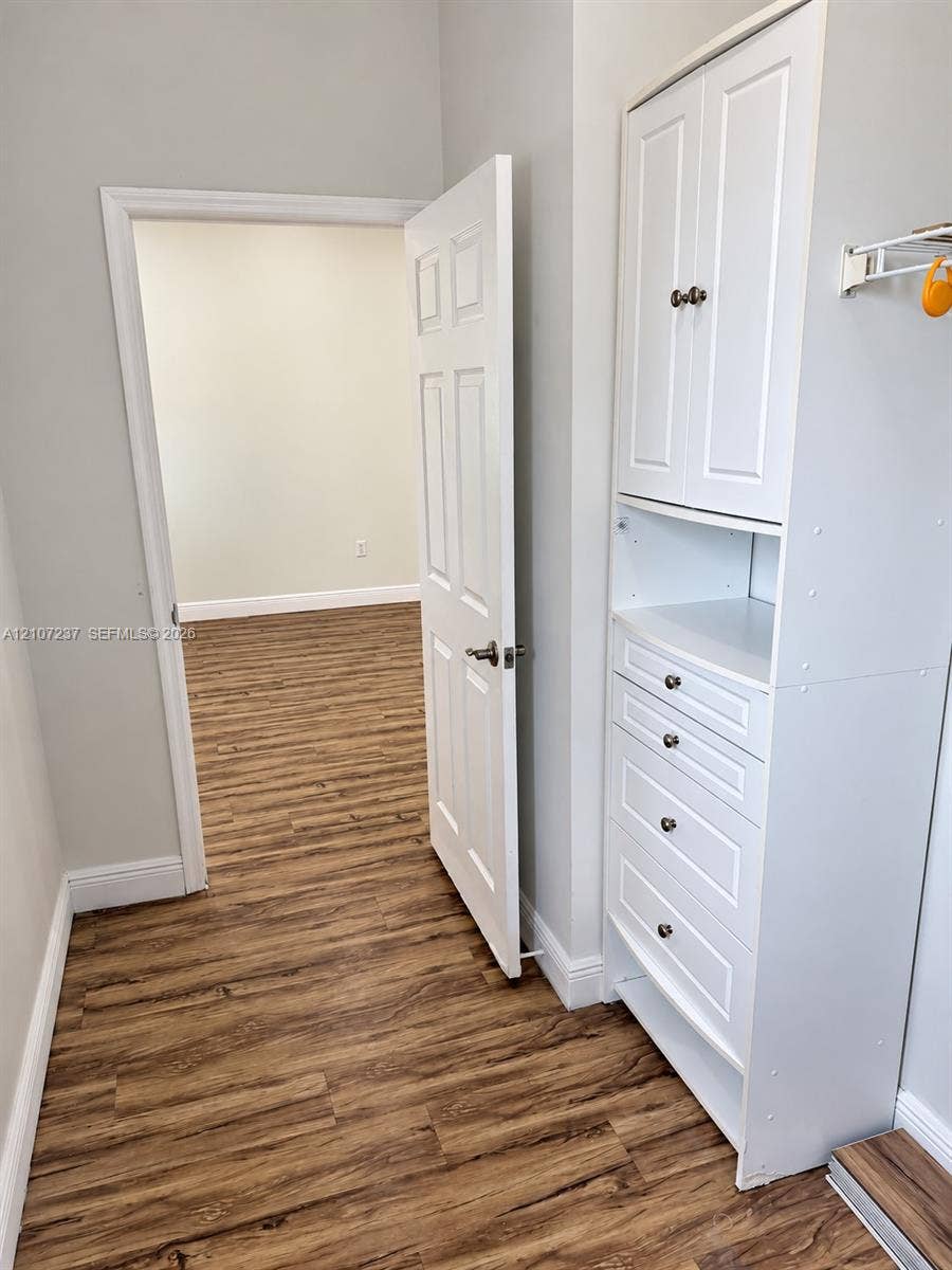 2529 NE 41st Terrace, Homestead, FL 33033 Built-in white storage cabinetry featuring shaker-style doors and multiple drawers, paired with wood-finish flooring and a six-panel door