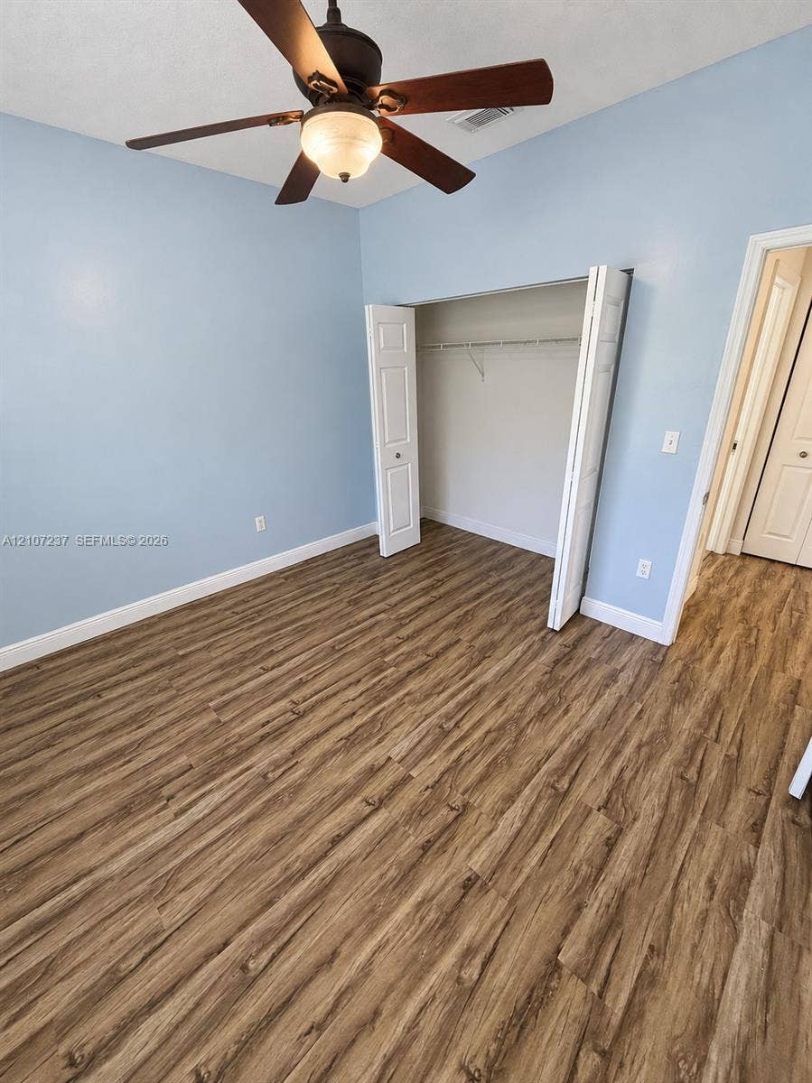 2529 NE 41st Terrace, Homestead, FL 33033 Room featuring wood-finish flooring, a ceiling fan with integrated light, and a closet with bifold doors