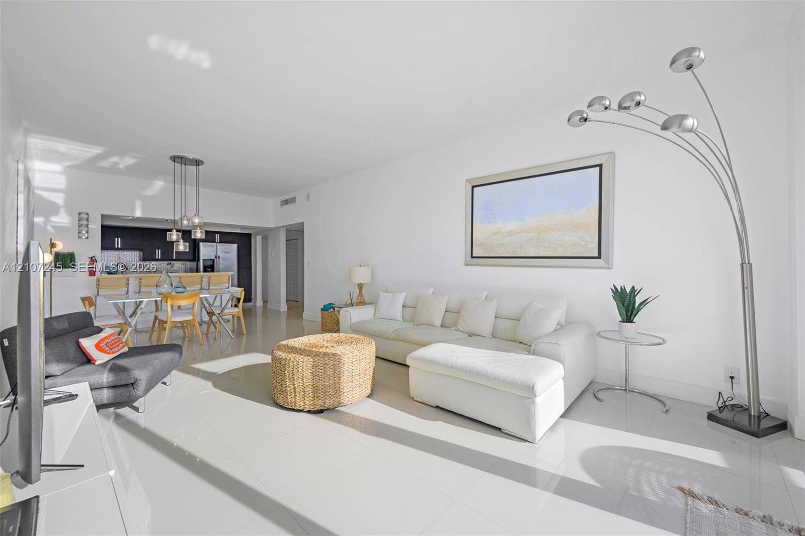 19370 Collins Avenue, #PH-14, Sunny Isles Beach, Sunny Isles Beach, FL 33160 Open-concept interior featuring large-format tile flooring, recessed ceiling lighting, and a kitchen equipped with dark cabinetry, integrated bar seating, and multi-pendant lighting