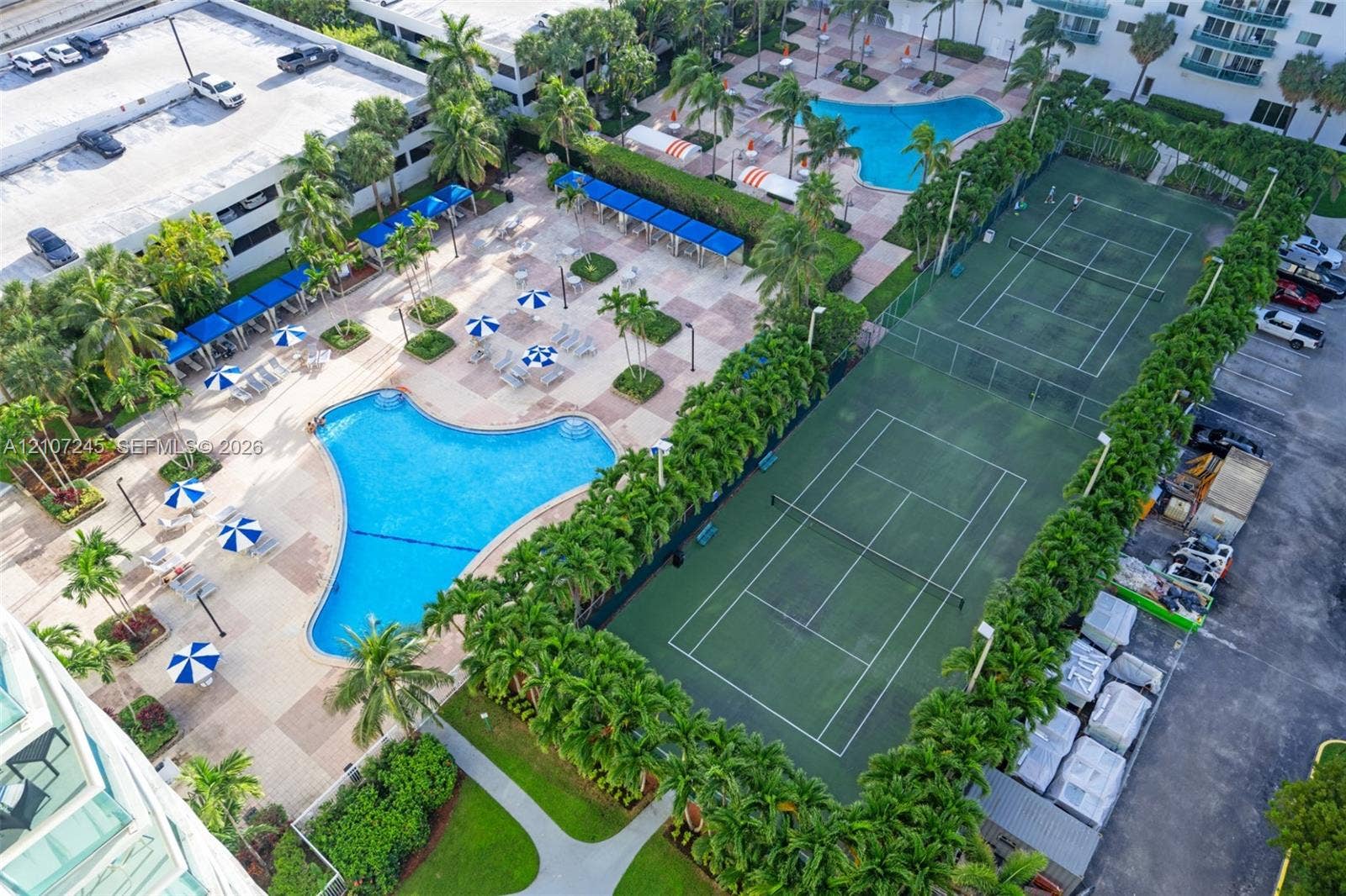 19370 Collins Avenue, #PH-14, Sunny Isles Beach, Sunny Isles Beach, FL 33160 Recreational area featuring two fenced tennis courts, two swimming pools, paved pool decks, and mature landscaping