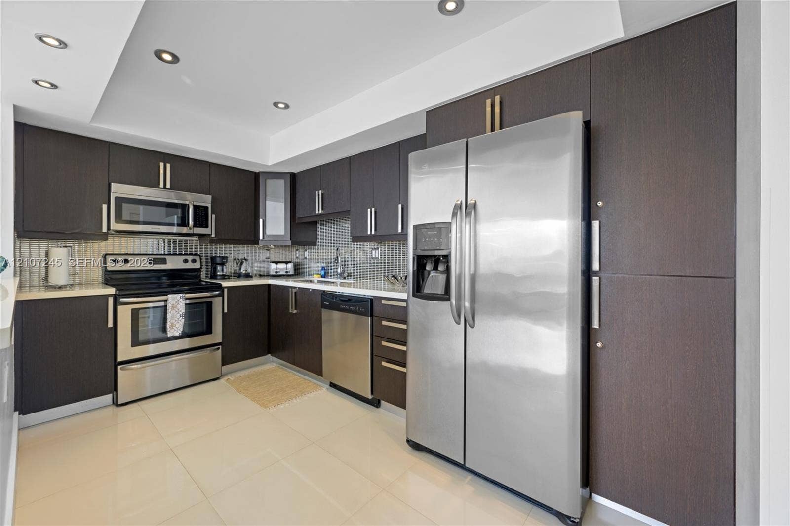19370 Collins Avenue, #PH-14, Sunny Isles Beach, Sunny Isles Beach, FL 33160 Kitchen featuring dark-toned flat-panel cabinetry, stainless steel appliances, tiled backsplash, light-toned flooring, and recessed ceiling lighting