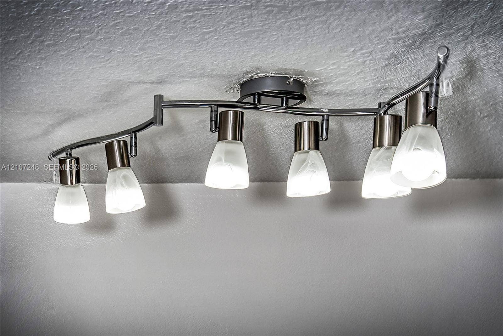 9983 W Atlantic Boulevard, #9983, Coral Springs, Coral Springs, FL 33071 Curved track lighting fixture featuring a brushed metal finish and six frosted glass shades