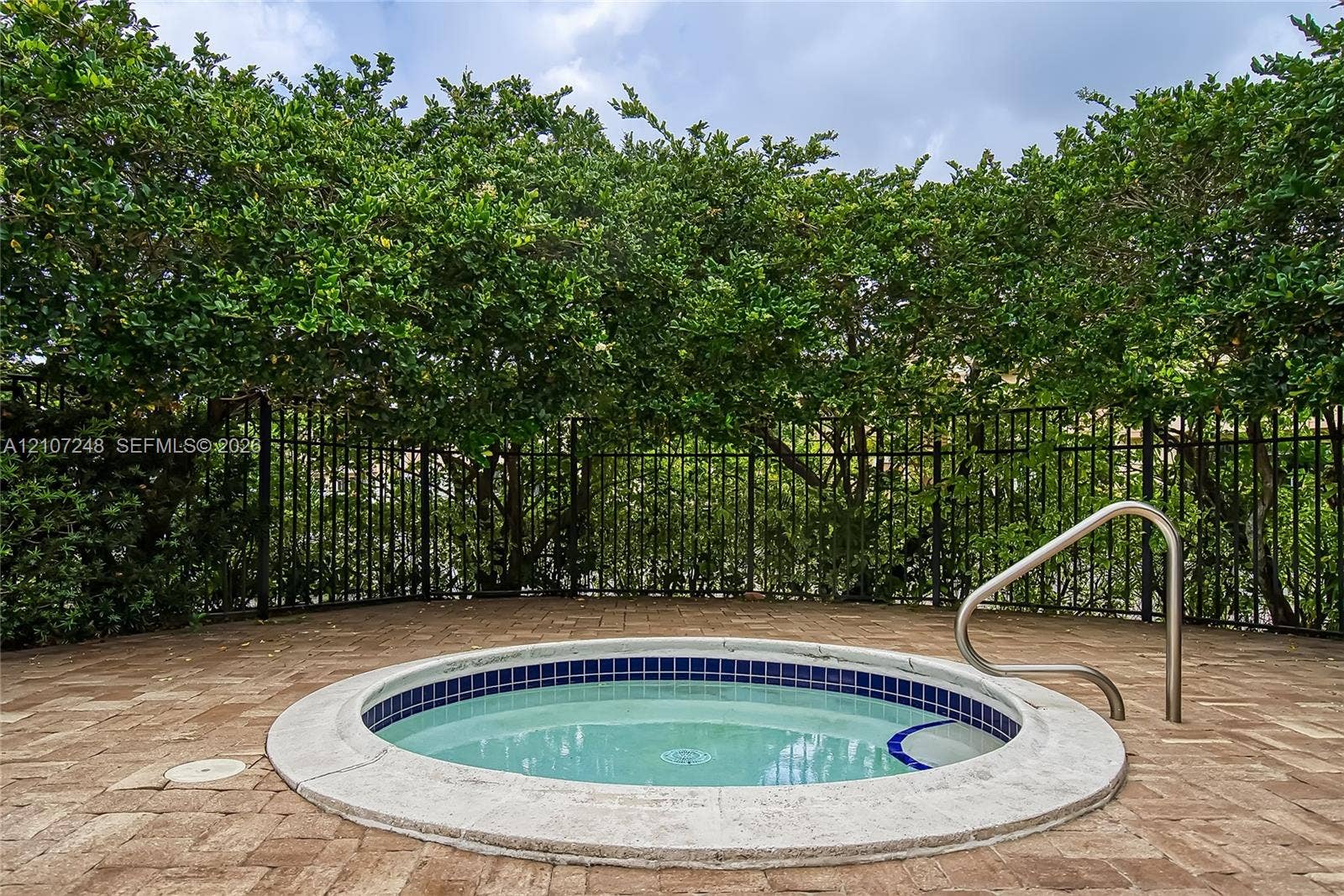 9983 W Atlantic Boulevard, #9983, Coral Springs, Coral Springs, FL 33071 In-ground spa featuring a stone-paver surround, metal safety railing, tile water-line finish, and integrated steps