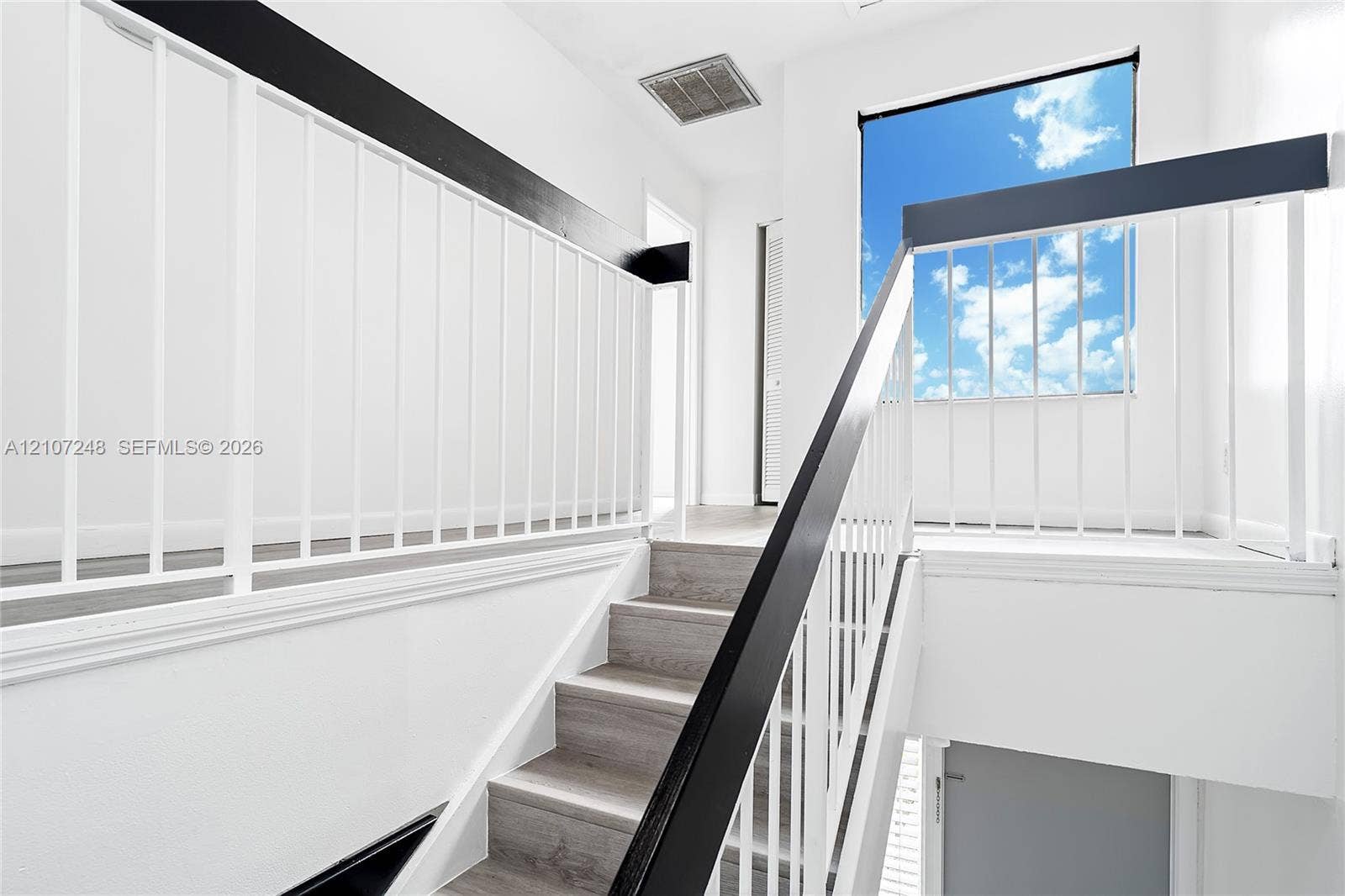 9983 W Atlantic Boulevard, #9983, Coral Springs, Coral Springs, FL 33071 Staircase featuring wood-finish treads, white metal balusters, and a bold black handrail