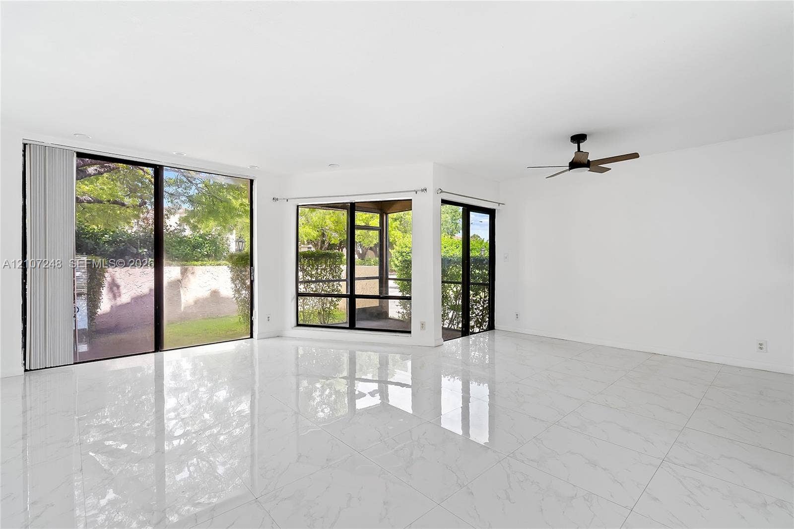 9983 W Atlantic Boulevard, #9983, Coral Springs, Coral Springs, FL 33071 Polished tile flooring with white-and-gray veining, expansive floor-to-ceiling glass sliding doors, dark-framed multi-pane windows, and a modern ceiling fan