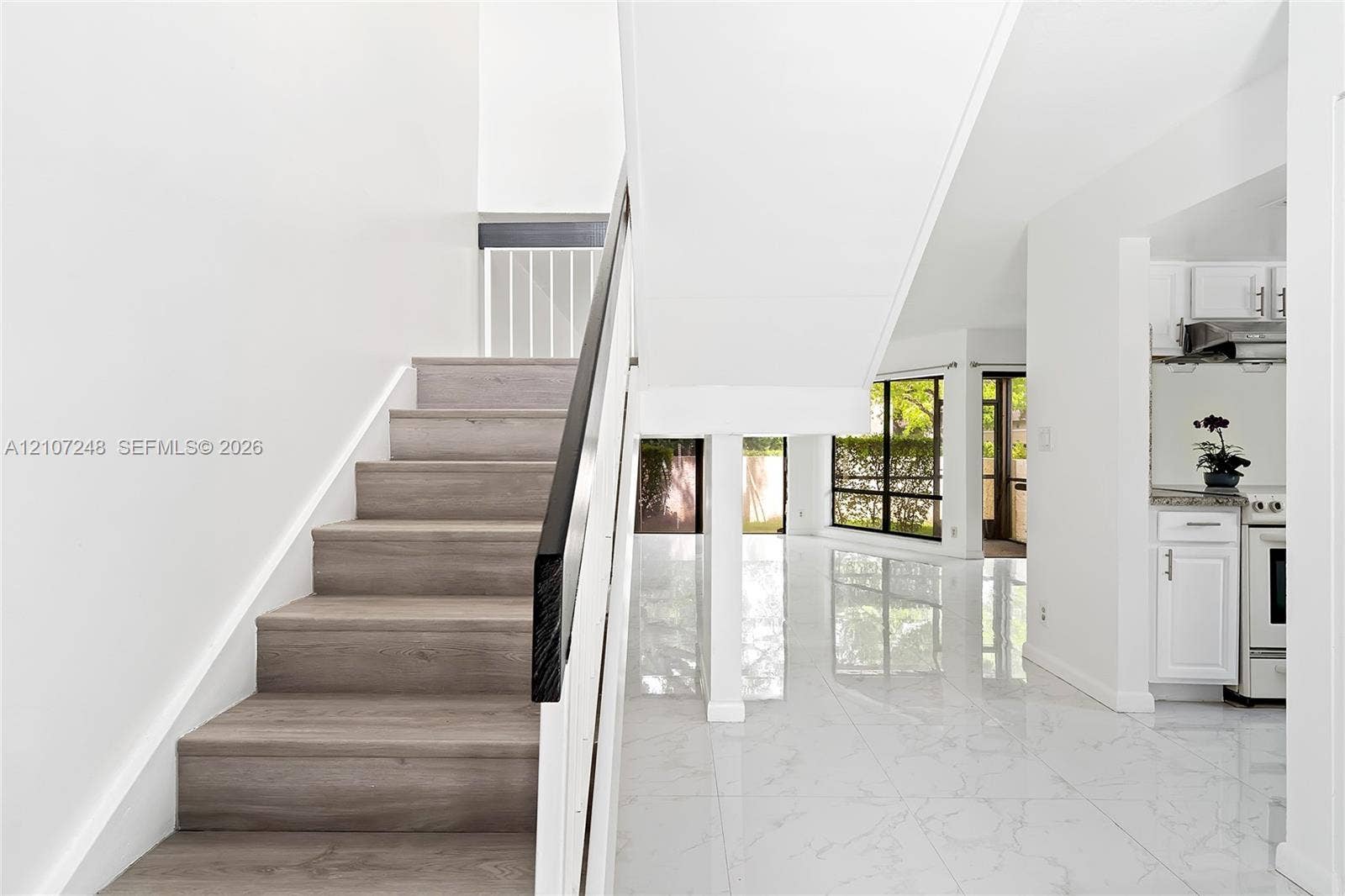 9983 W Atlantic Boulevard, #9983, Coral Springs, Coral Springs, FL 33071 Staircase with wood-finish treads and black handrail, high-gloss polished tile flooring, and large window wall