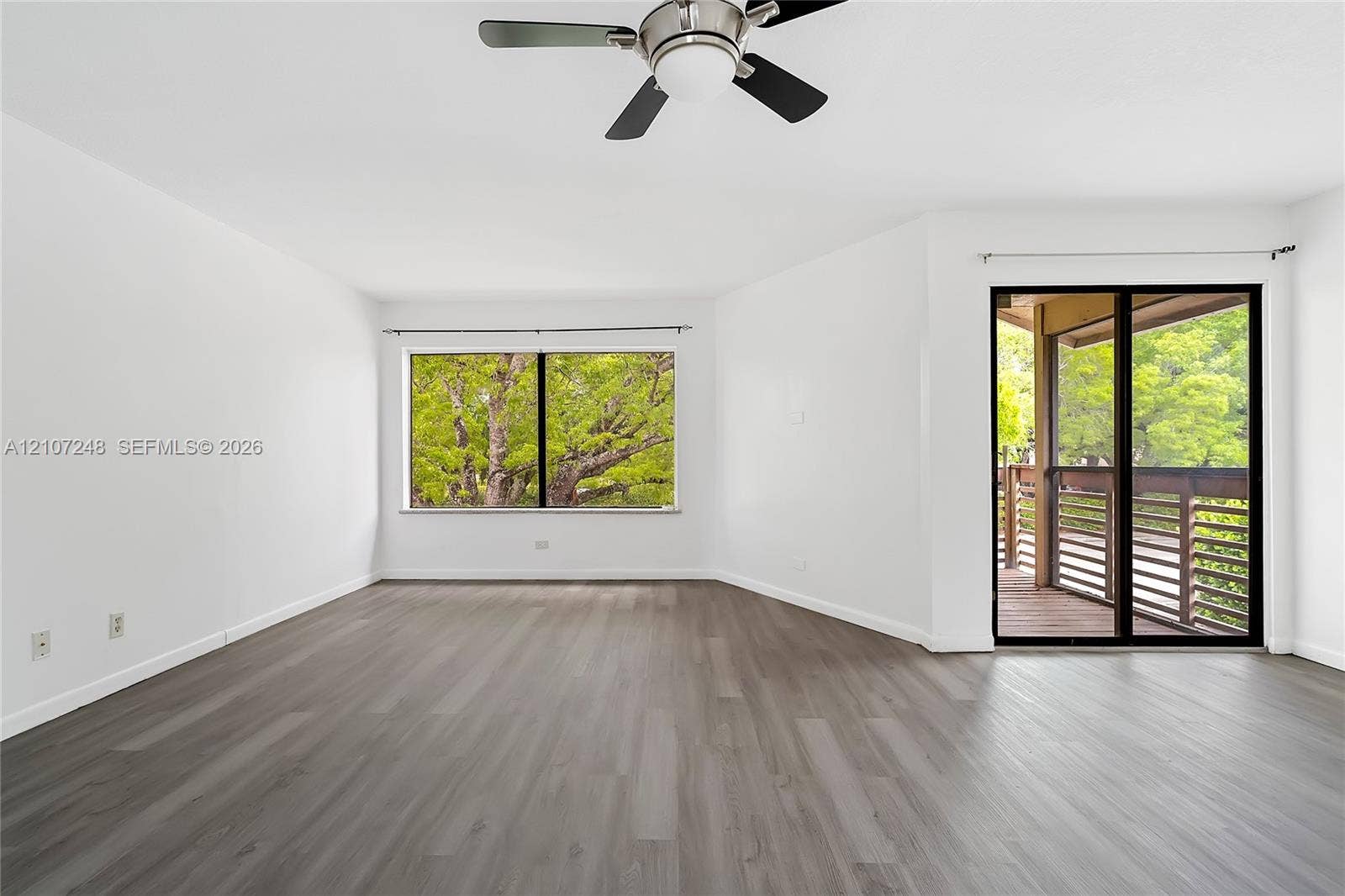 9983 W Atlantic Boulevard, #9983, Coral Springs, Coral Springs, FL 33071 Neutral interior featuring wood-finish flooring, a ceiling fan, a large window, and sliding glass doors with direct access to a covered deck